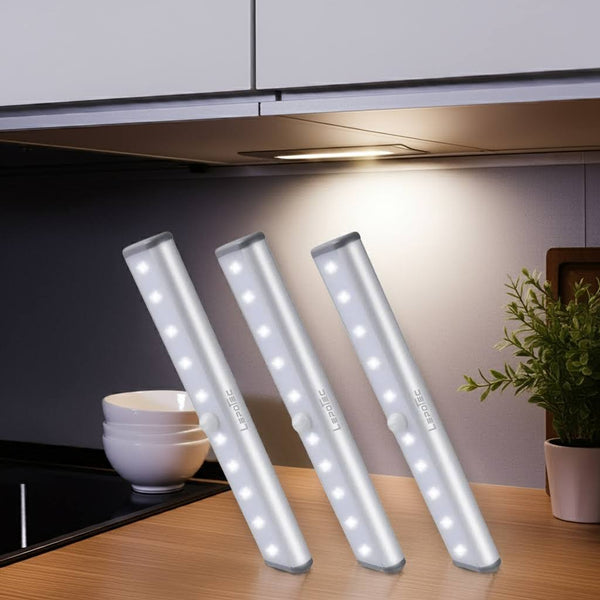 Three under-cabinet LED lights on a kitchen counter with a plant and bowls in the background.