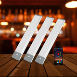 Three LED strip lights on a wooden surface with a smartphone displaying app interface in the background.