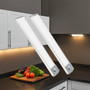 Two white LED strip lights on a kitchen counter with vegetables on a cutting board.
