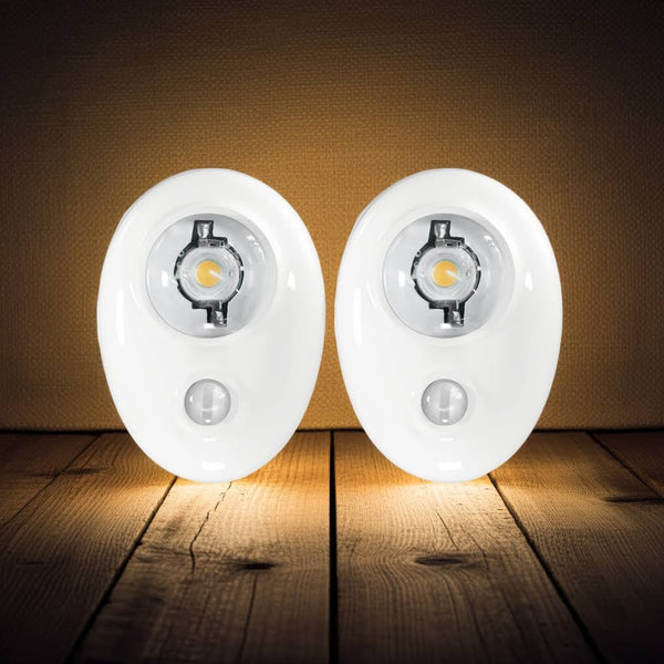 Two motion sensor lights on a wooden surface with a dark background