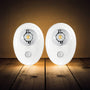 Two motion sensor lights on a wooden surface with a dark background