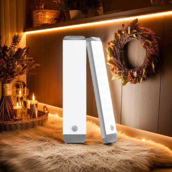 Two white LED night lights on a wooden surface with decorative elements like candles and a wreath.